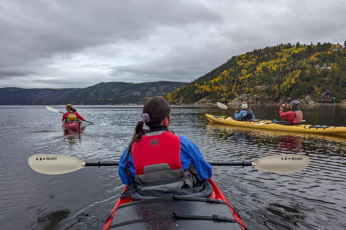 Plusieurs personnes qui font une sortie kayak en mer au coucher du soleil dans le fjord du Saguenay