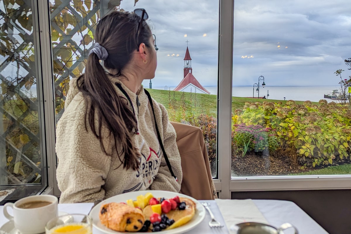 Personne qui prend son petit-déjeuner dans l'Hôtel de Tadoussac avec vue sur la baie et la Chapelle