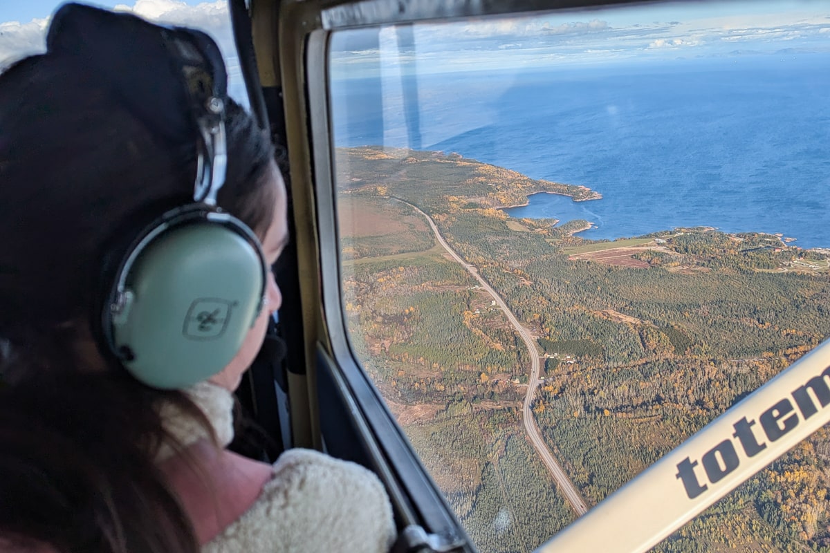 Personne qui regarde la vue pendant un vol au dessus de Tadoussac et les alentours